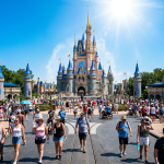 Crowd of people walking and standing near large fairy tale castle with blue spires